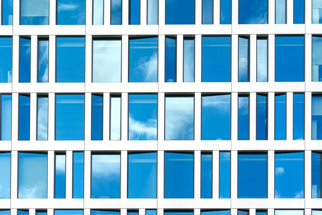 Fachada acristalada de un edificio de oficinas reflejando el cielo