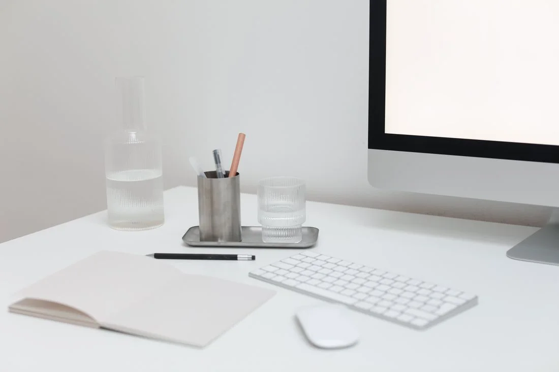 Escritorio despejado con pantalla, teclado y cuaderno abierto