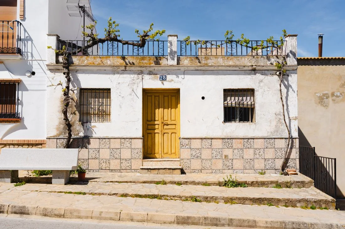 Fachada de una casa de pueblo española, encalada y con zócalo de azulejos