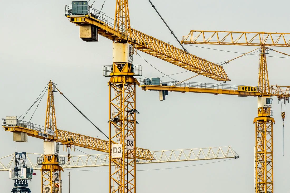 Varias grúas torre amarillas trabajando en una promoción de viviendas