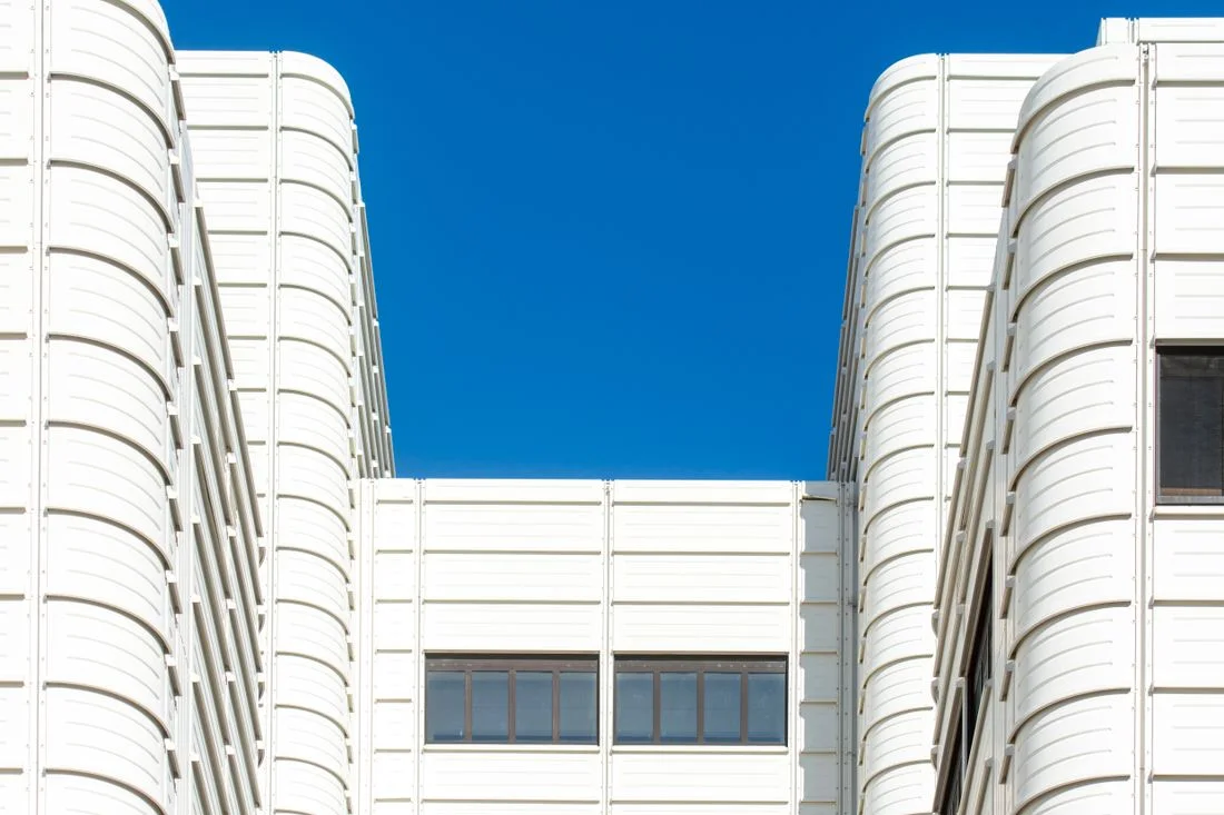 Fachada blanca de un edificio público moderno bajo cielo azul