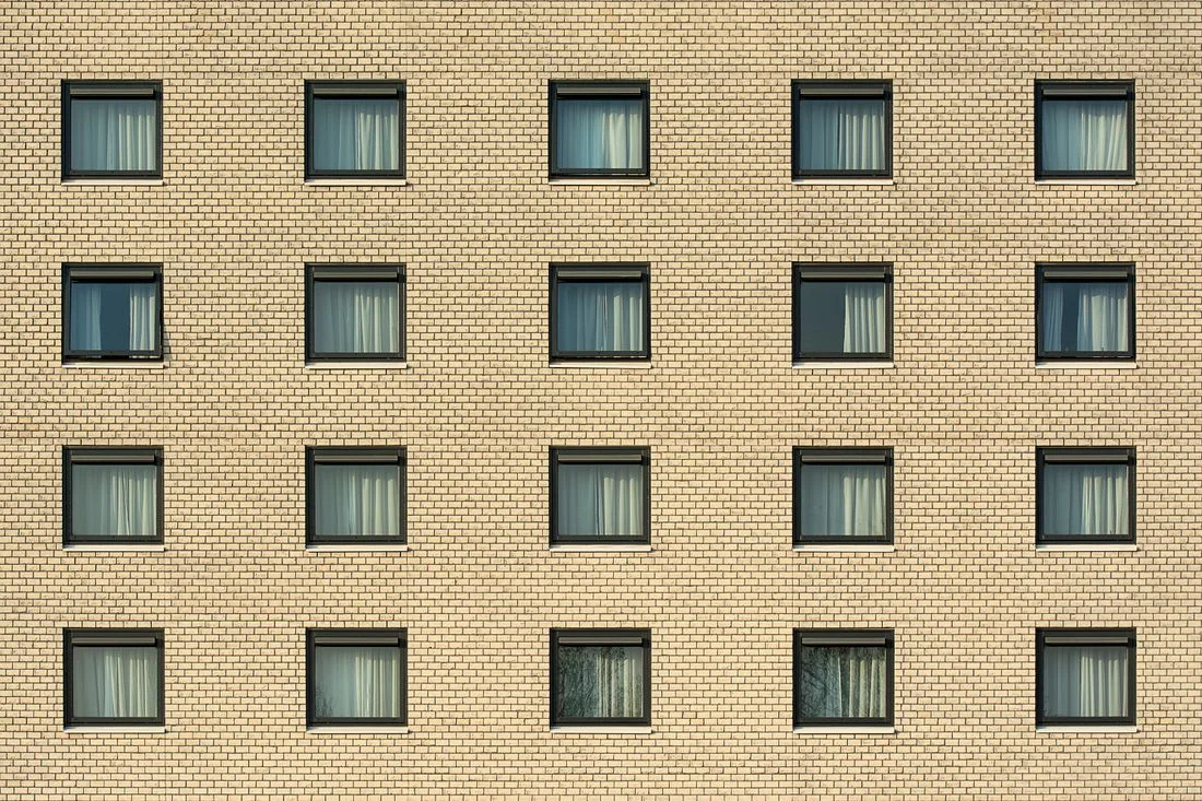 Fachada de ladrillo con decenas de ventanas idénticas alineadas en retícula
