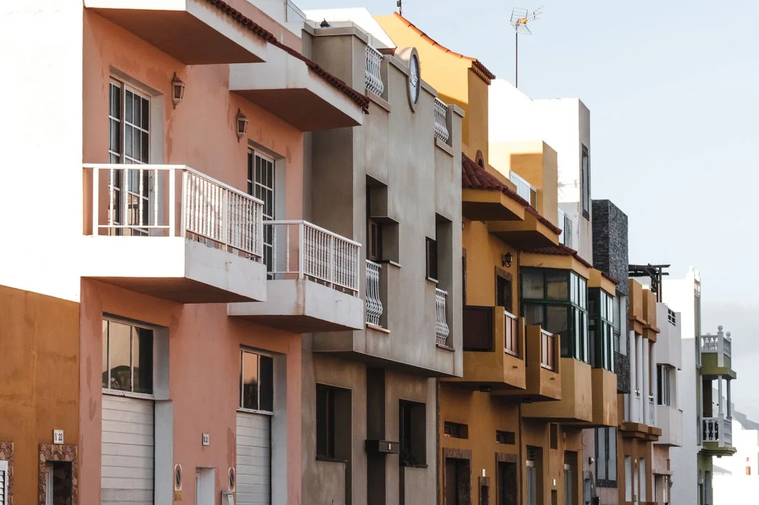 Hilera de edificios residenciales españoles con balcones y fachadas de colores