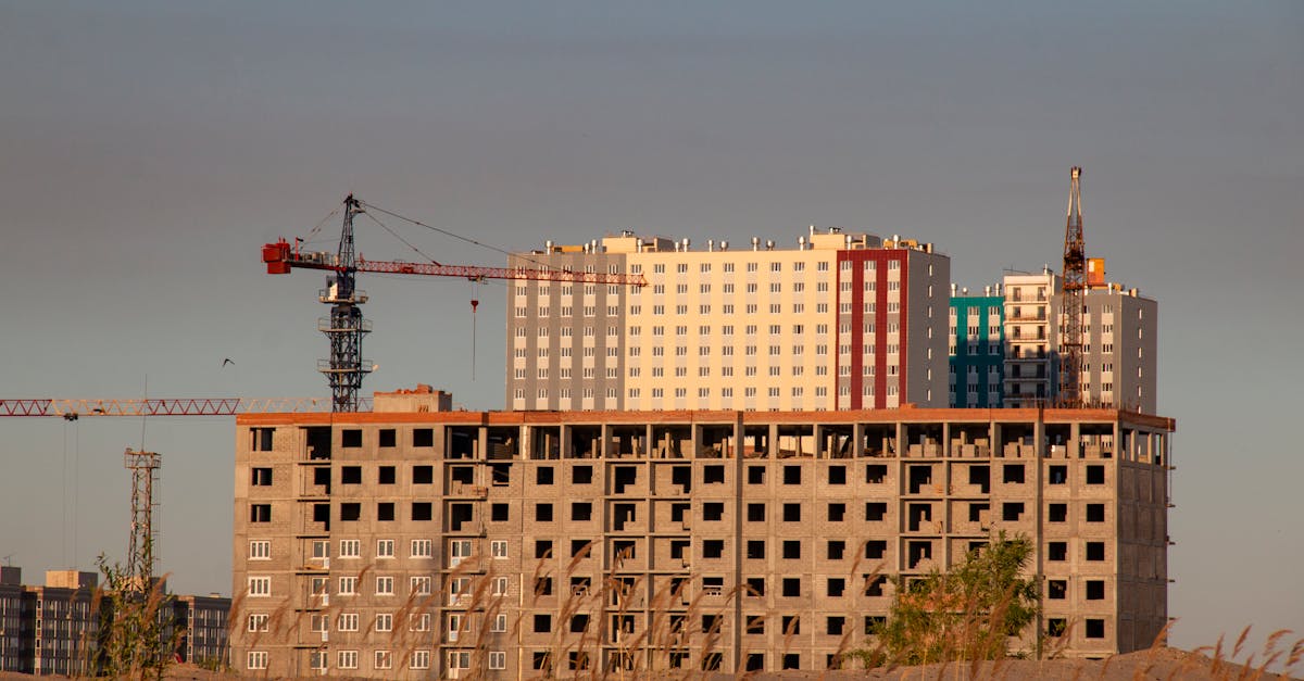 High-rise building under construction with cranes against a clear sky.