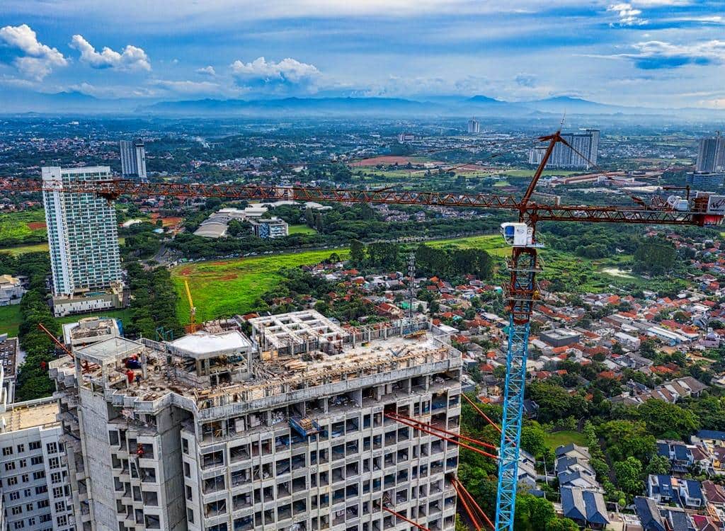 Suelo bloqueado vivienda España 2026: parcelas sin urbanizar frente a grúas de construcción en Madrid